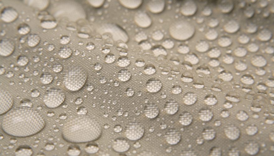 Macro shot of water drops pearling on waterproof nylon jacket. Short DOF.